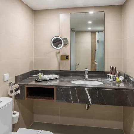 Makarem Ajyad Makkah Hotel Mecca Exterior photo The photo shows a modern bathroom with a clean and minimalist design. It features a white toilet and a sleek vanity area with a dark marble countertop. A round mirror is mounted above the sink, which has a contemporary faucet. The sink area is arrang
