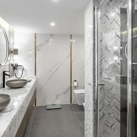 Makarem Ajyad Makkah Hotel Mecca Exterior photo The photo displays a modern bathroom featuring a clean and elegant design. There are two round mirrors above a marble countertop, which holds two stylish, bowl-shaped sinks. The walls are adorned with textured marble, and the flooring appears to be a